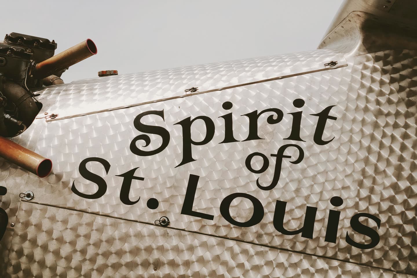 The Spirit of St. Louis aircraft fuselage with the original lettering, against a pale sky
